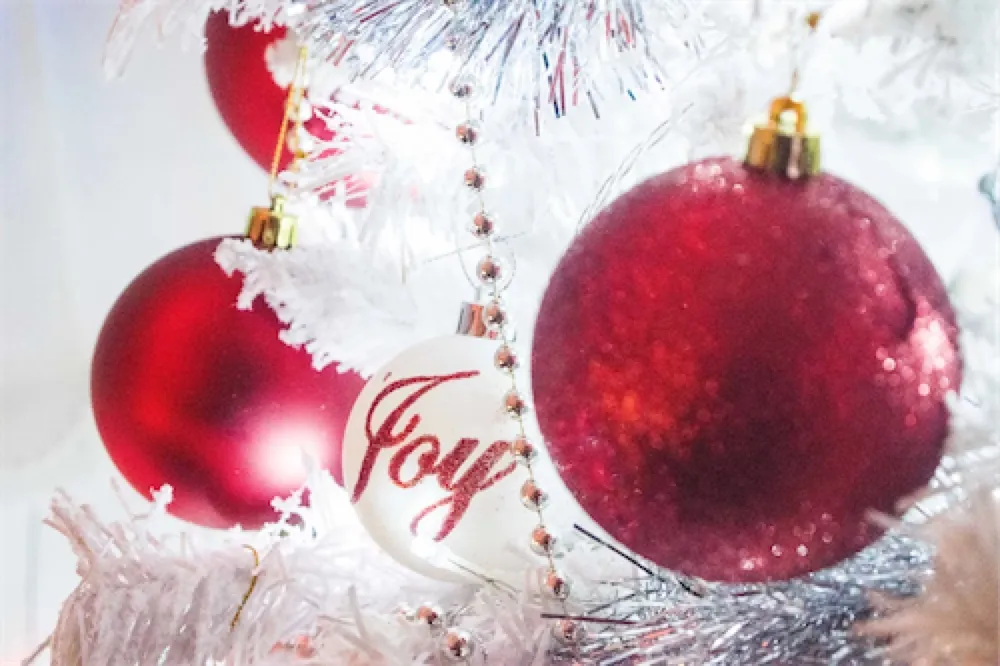 Red Christmas baubles on a tree, one reading Joy
