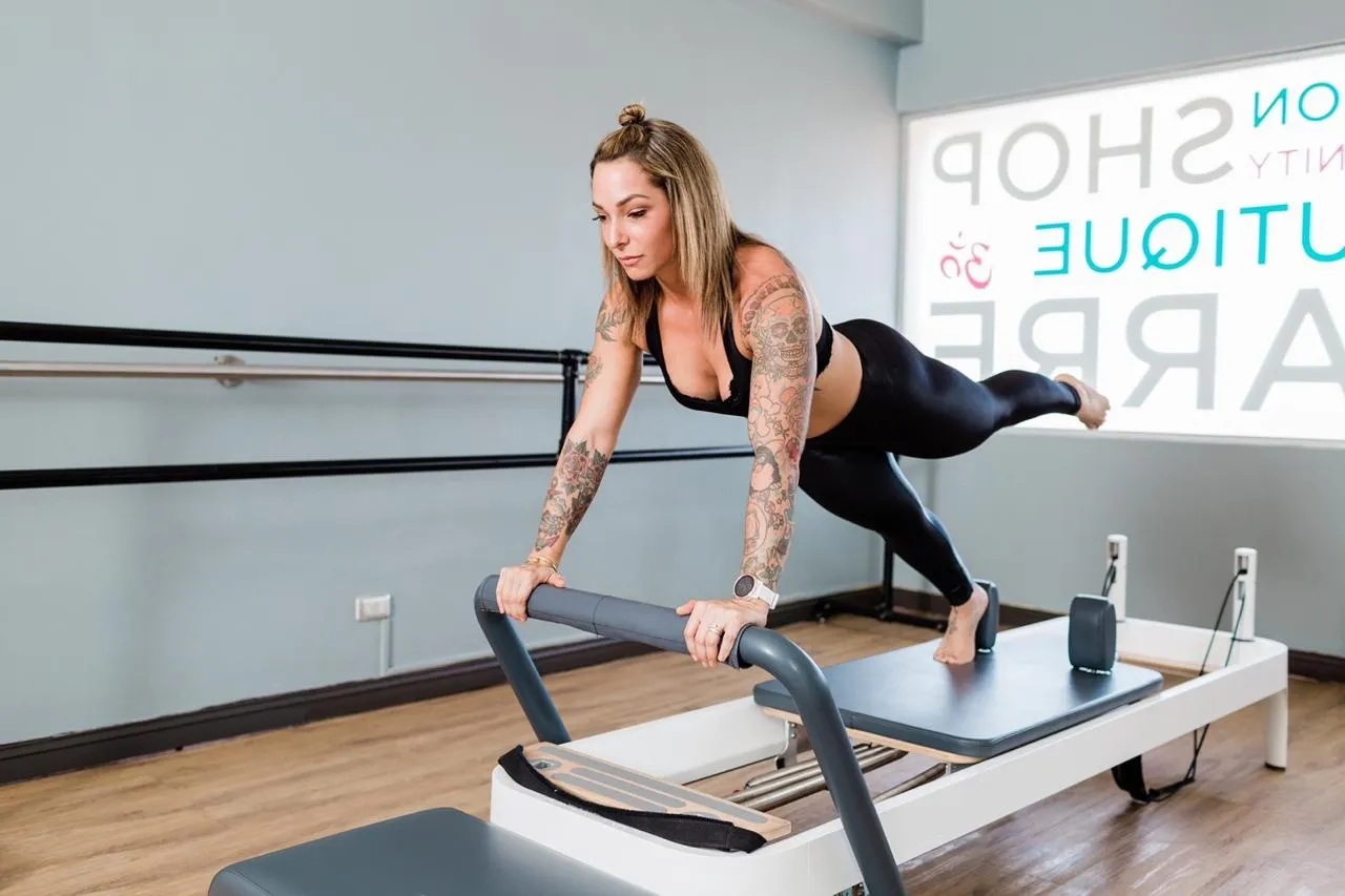 Woman holding a plank on a Pilates reformer in a studio