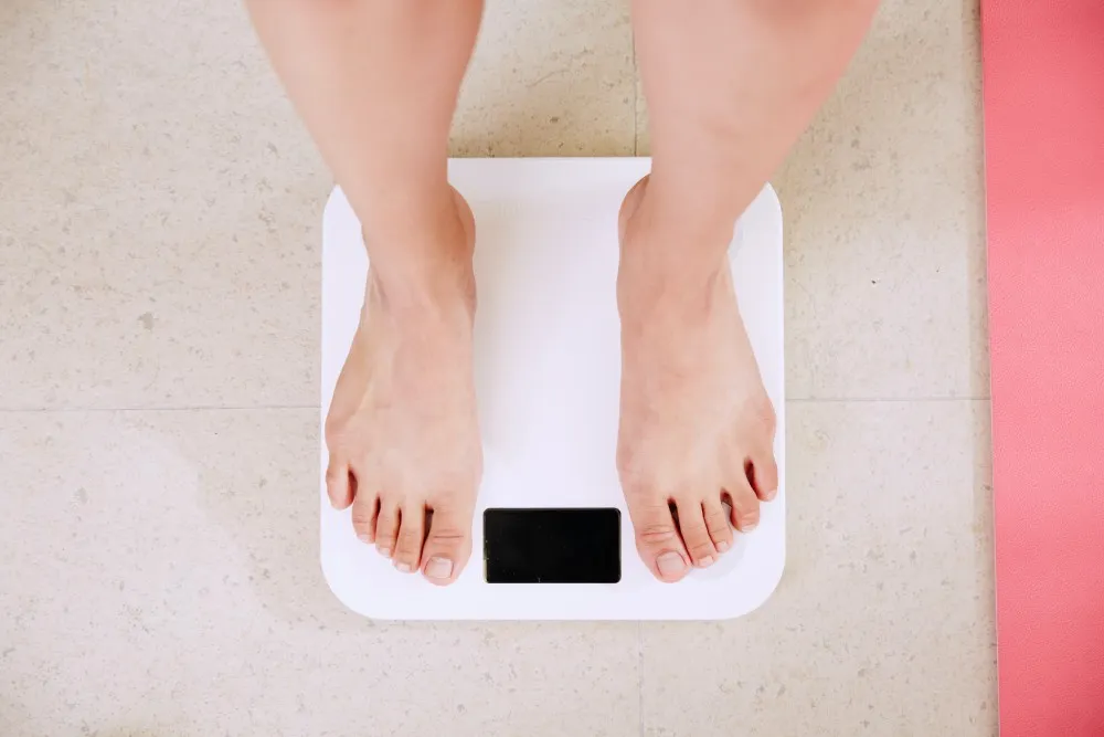 Bare feet standing on a white bathroom scale