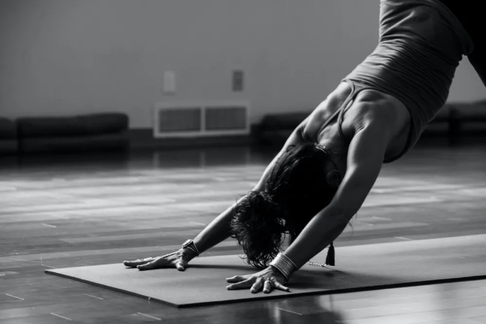 Black and white photo of a person in downward facing dog on a yoga mat
