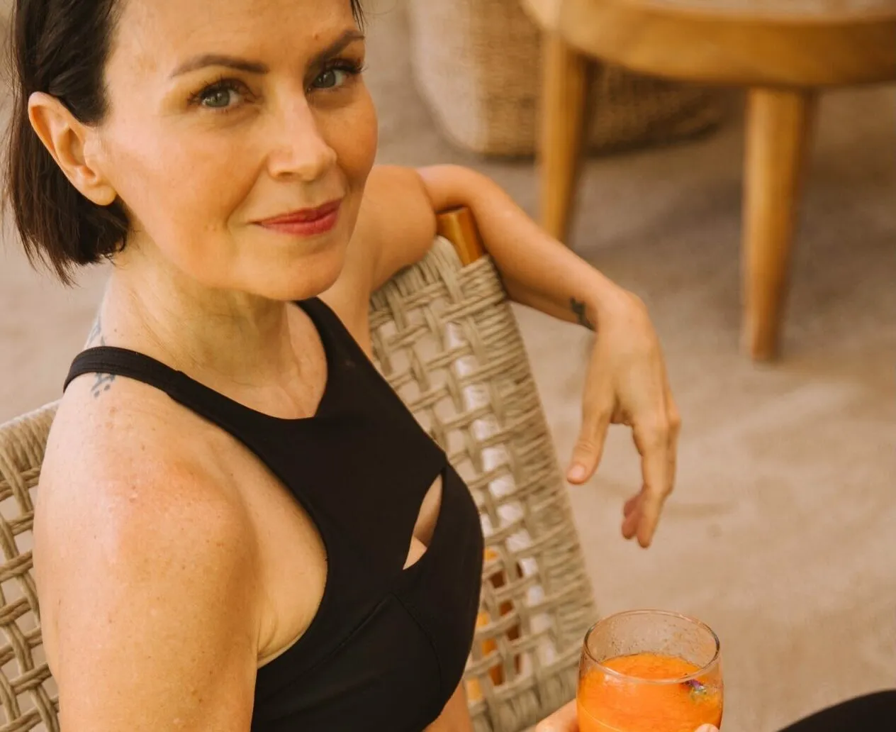 Smiling woman in a black top holding a glass of orange juice